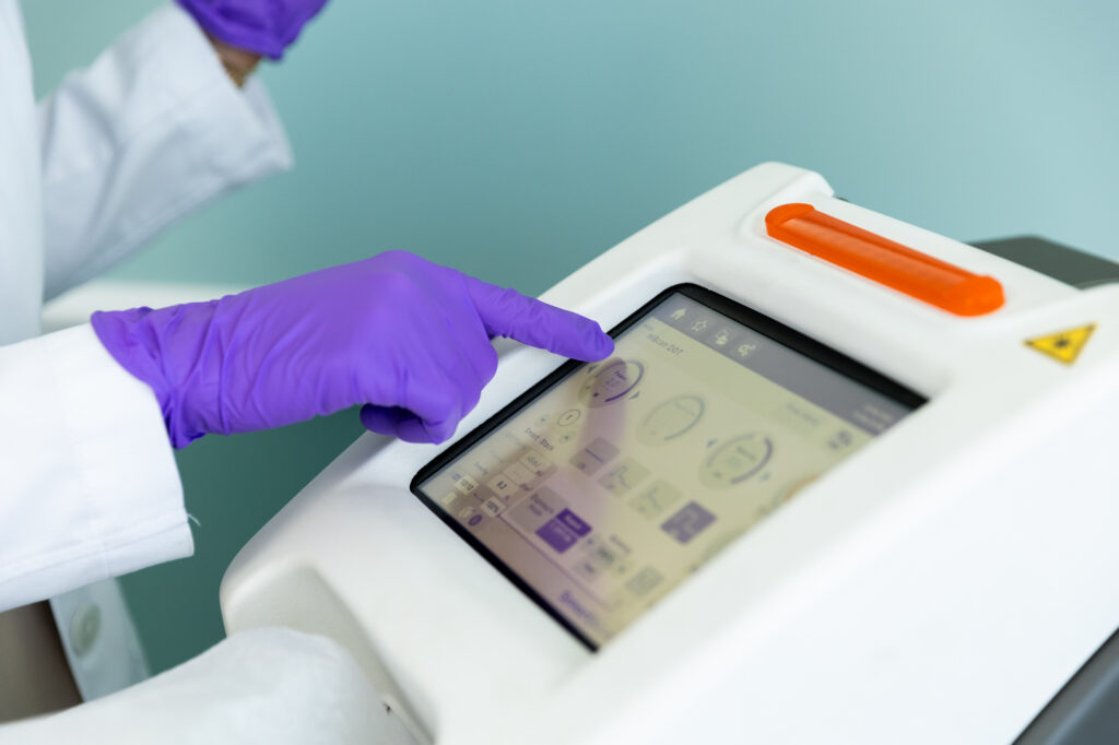 One of our expert providers wearing purple gloves adjusts the settings on our device for laser resurfacing in St. Petersburg.