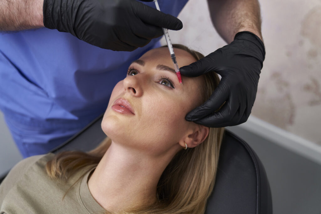 A woman is lying down in a chair and receiving Botox injections after searching "Botox near me" and discovering Hermann Aesthetics.