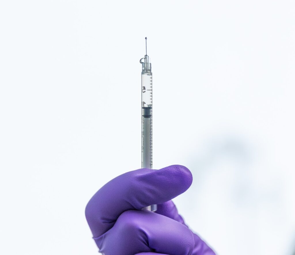 A provider's hand with a purple glove on holds up a syringe, preparing to use Botox for TMJ in St. Petersburg.
